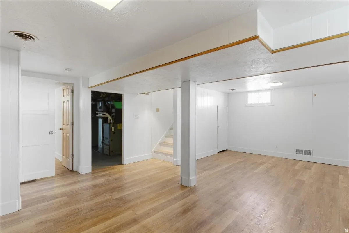 Finished lower level featuring wood-finish flooring, white paneled walls, and recessed lighting