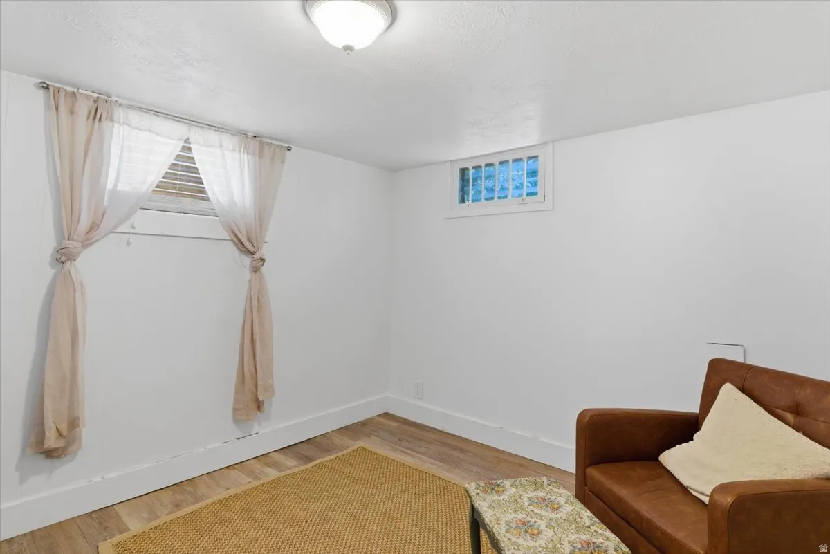 Light-filled room featuring white walls, wood-finish flooring, and white baseboards