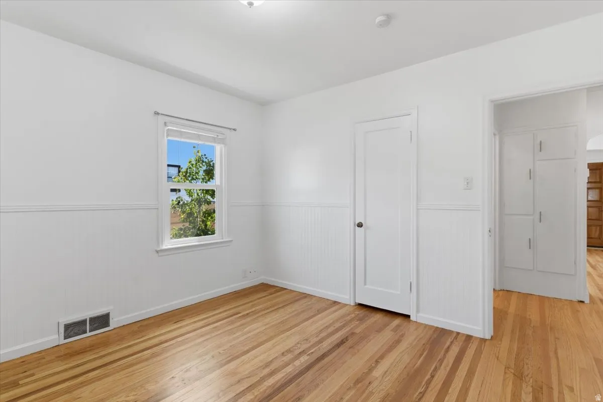 Room featuring wood-finish flooring, white beadboard wainscoting, and a white-framed window