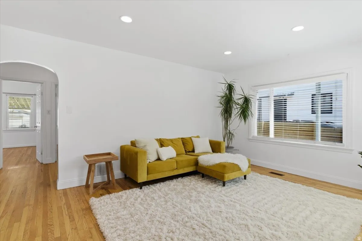 Spacious room featuring wood-finish flooring, recessed lighting, and a large window with white blinds