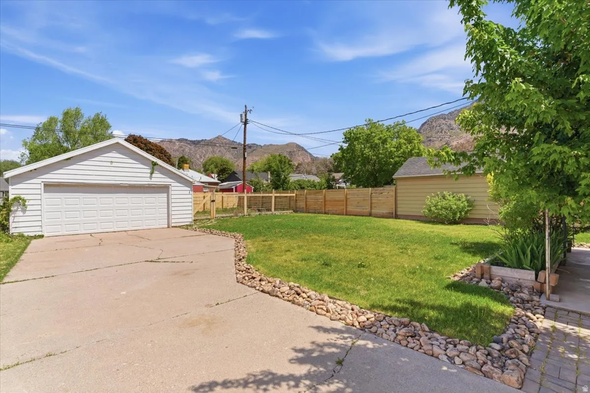 Detached garage with a two-car overhead door, concrete driveway, and a fenced yard with natural wood privacy fencing