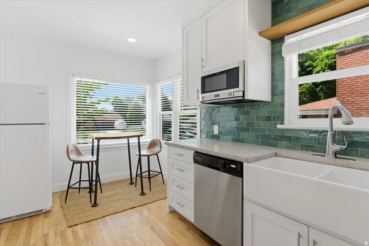 Contemporary kitchen with hardwood-finish flooring, white cabinetry, and stainless steel appliances