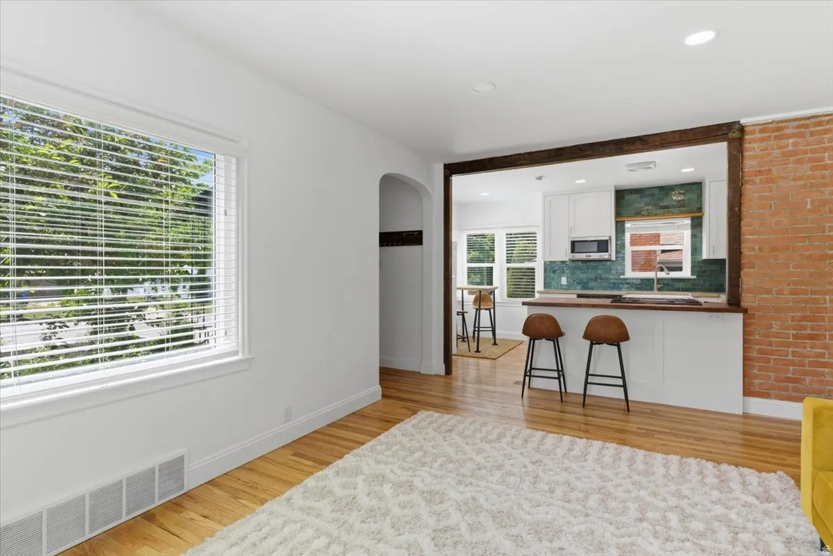 Hardwood flooring extends from the foreground into an archway and kitchen beyond