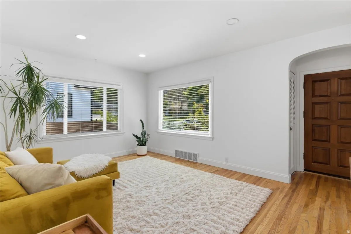 Bright living space featuring natural wood flooring, recessed lighting, white walls, and multiple windows