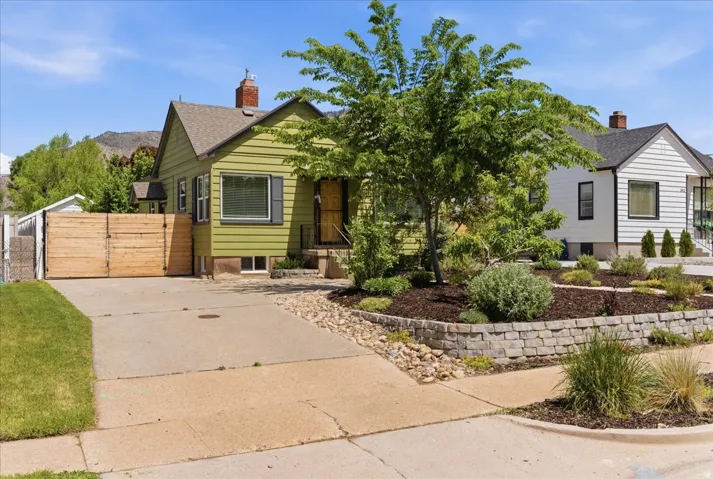Lime green siding exterior with dark shutters, gabled roofline, and red brick chimney