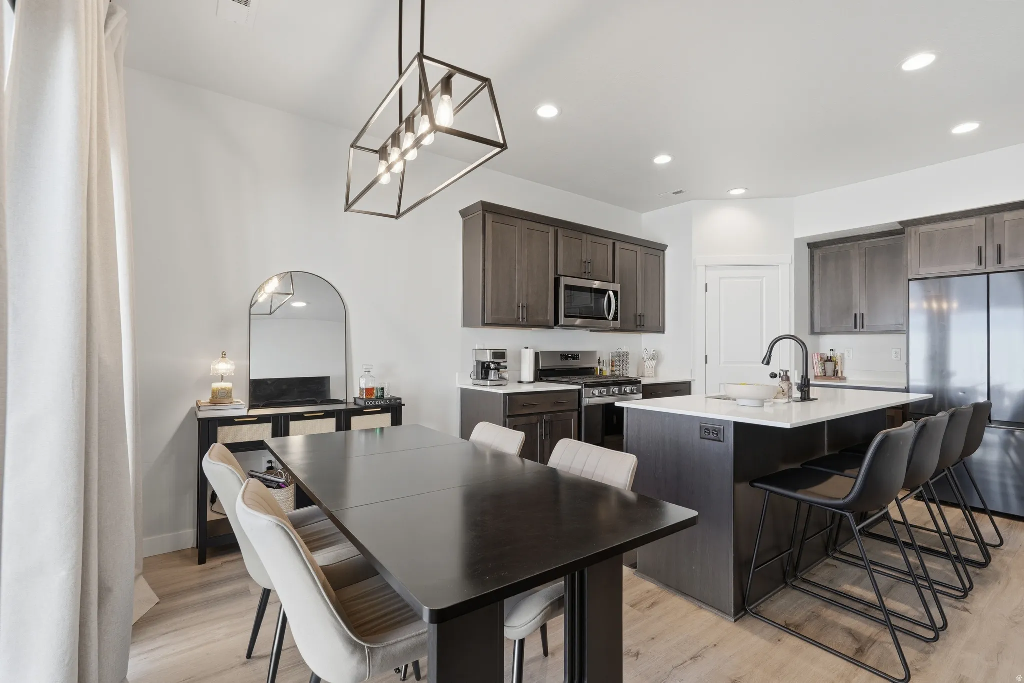 Open-concept kitchen and dining area featuring wood-finish flooring, recessed lighting, and a linear pendant light fixture