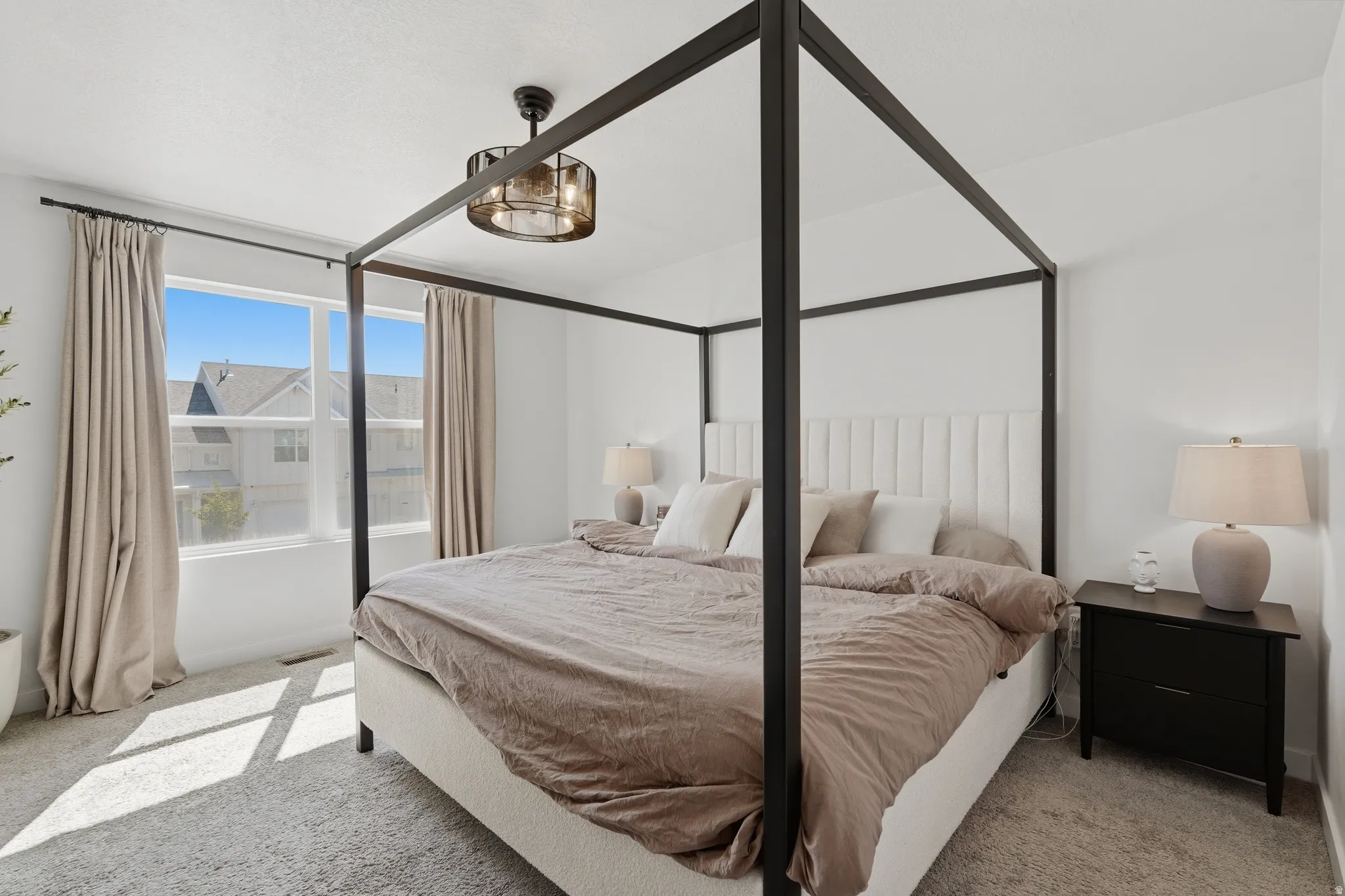 Bright bedroom featuring a large window, soft carpeting, and a ceiling-mounted light fixture
