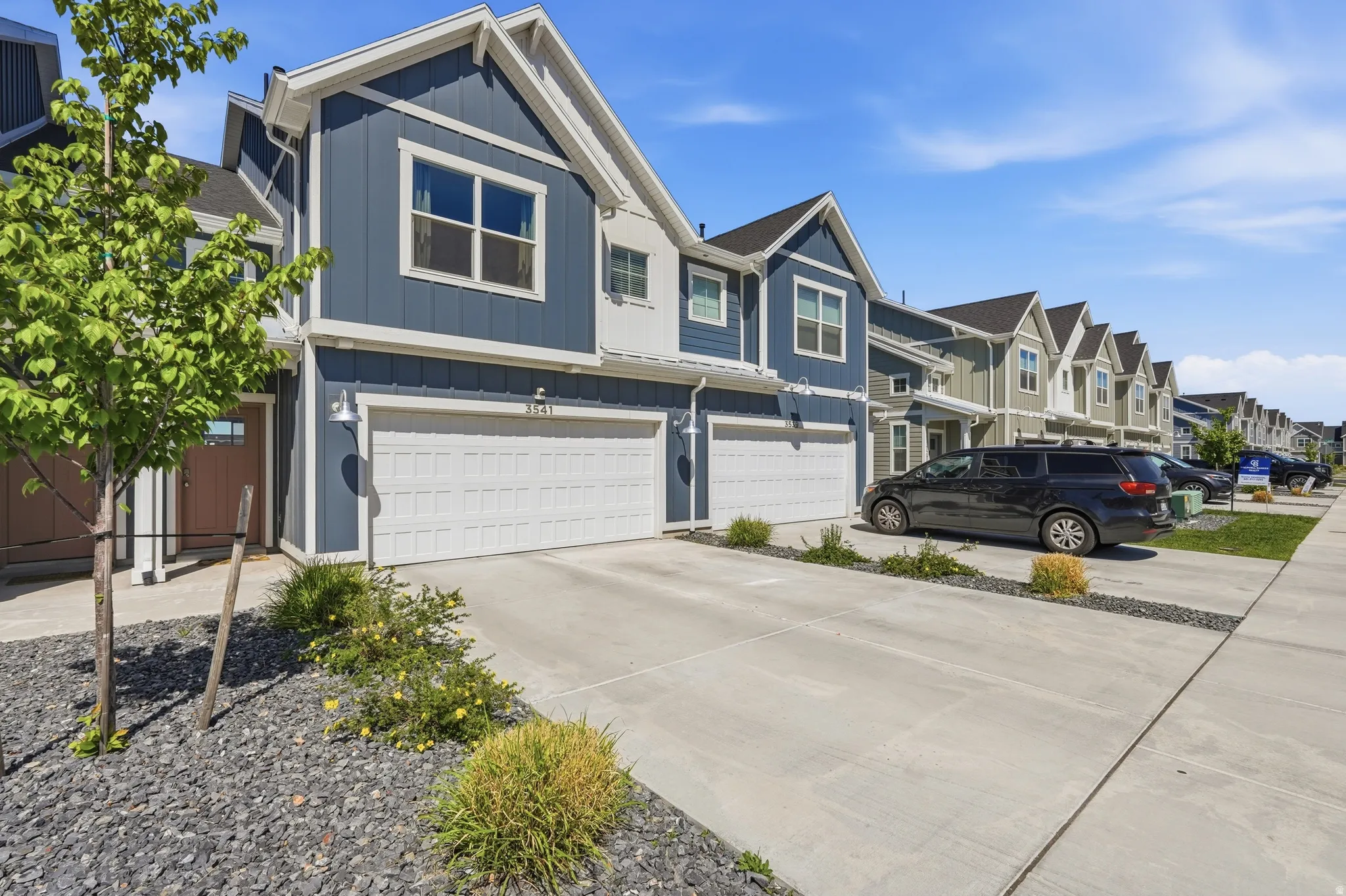 Contemporary townhouse exterior featuring blue vertical and horizontal siding, white trim, and a prominent gable roofline
