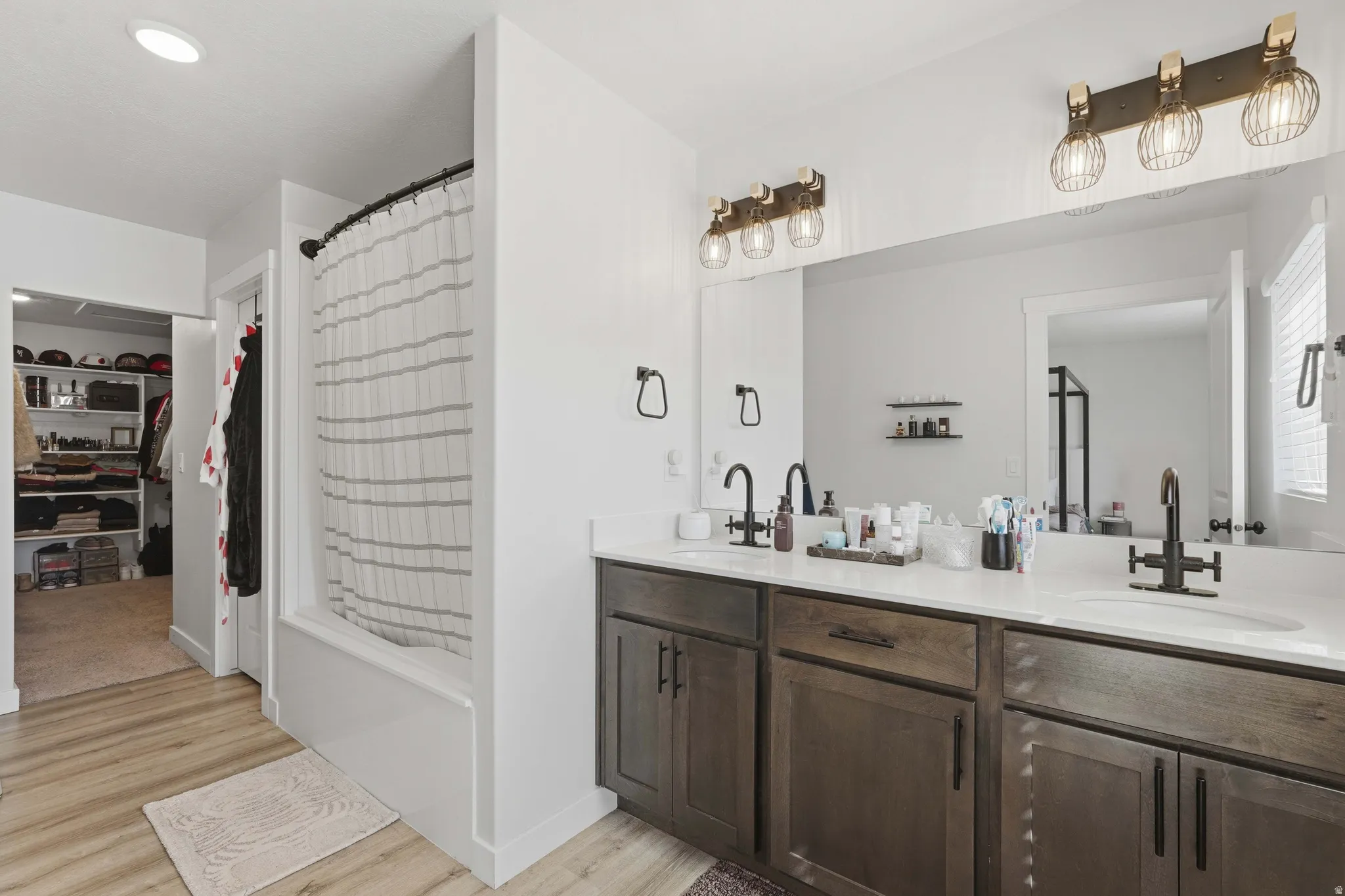 Dual vanity with dark wood-finish cabinetry, white countertop, and matte black fixtures