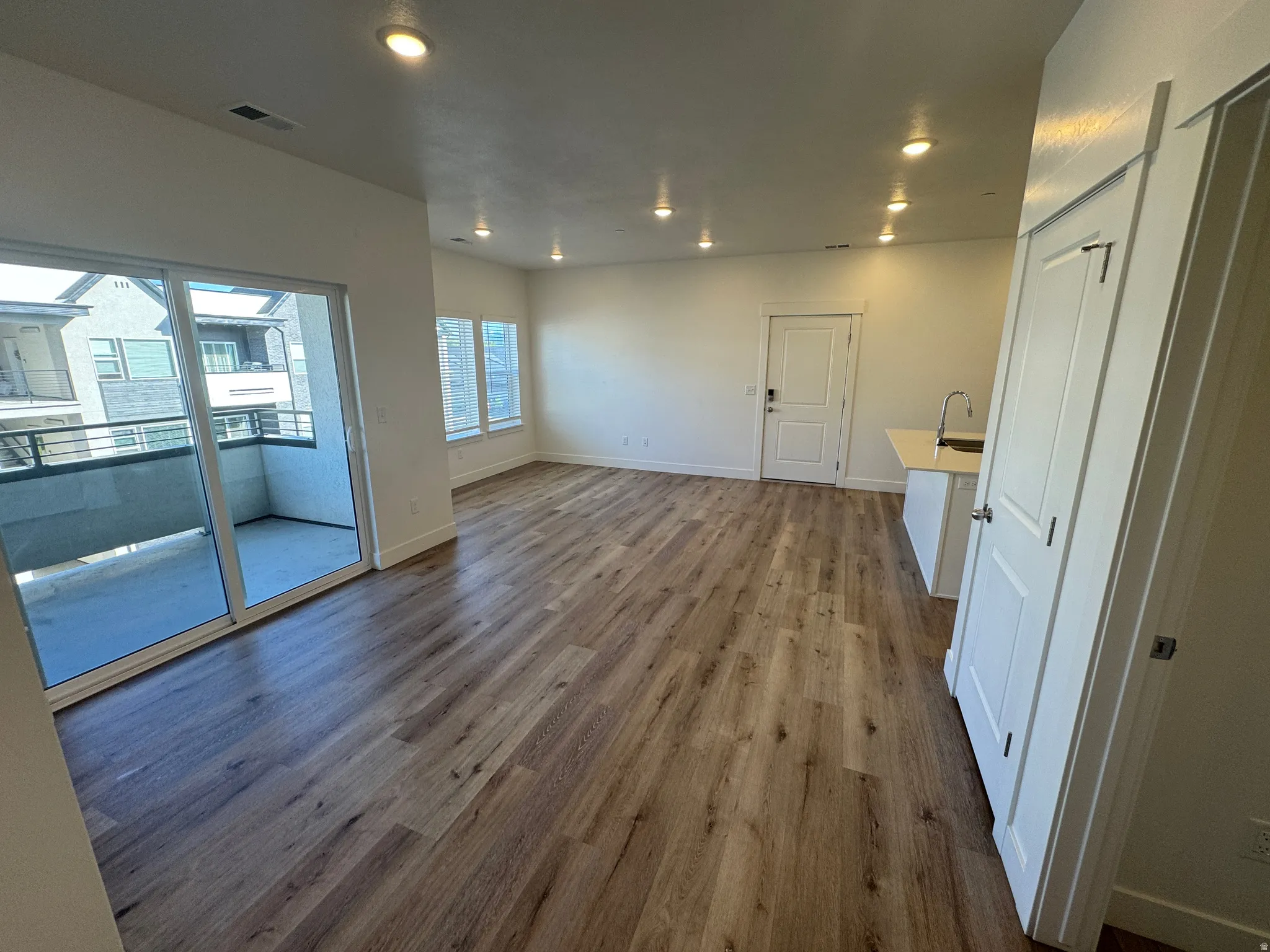 Open-concept living area featuring wood-finish flooring, recessed lighting, and multiple windows