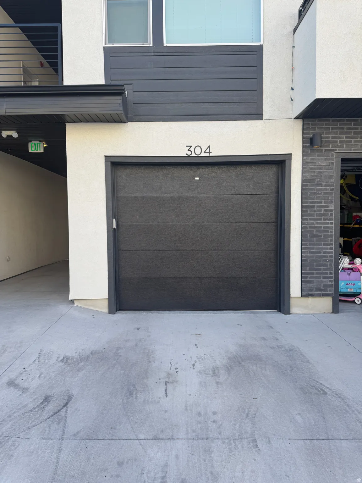 Modern exterior featuring a dark gray garage door with prominent house numbers