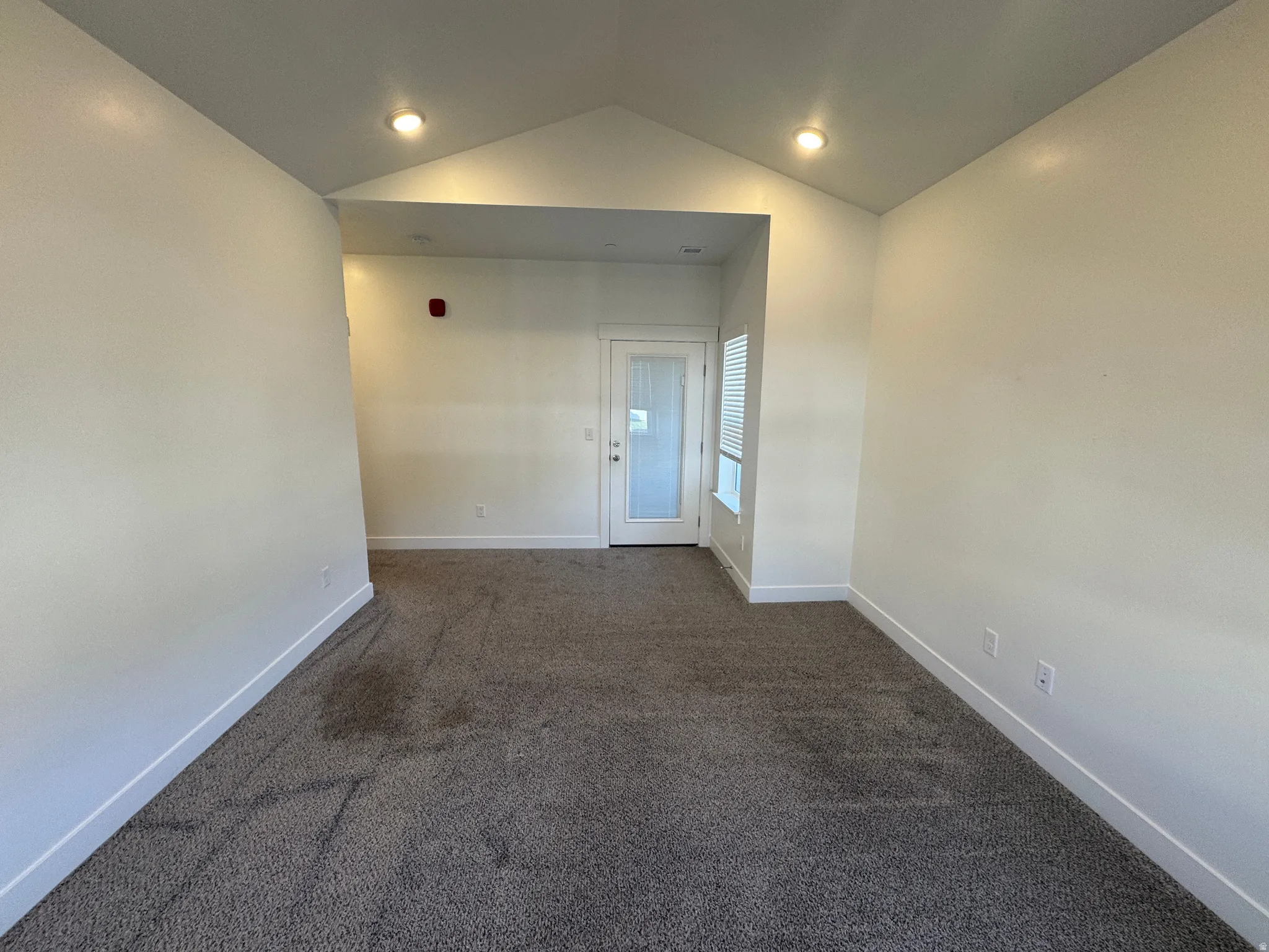 Spacious room with a vaulted ceiling and recessed lighting