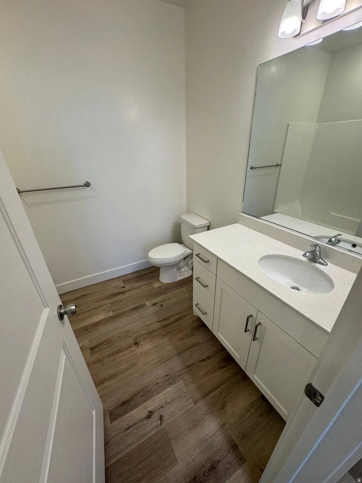 Bathroom featuring wood-finish flooring, a white vanity with a light-colored countertop, and a recessed sink