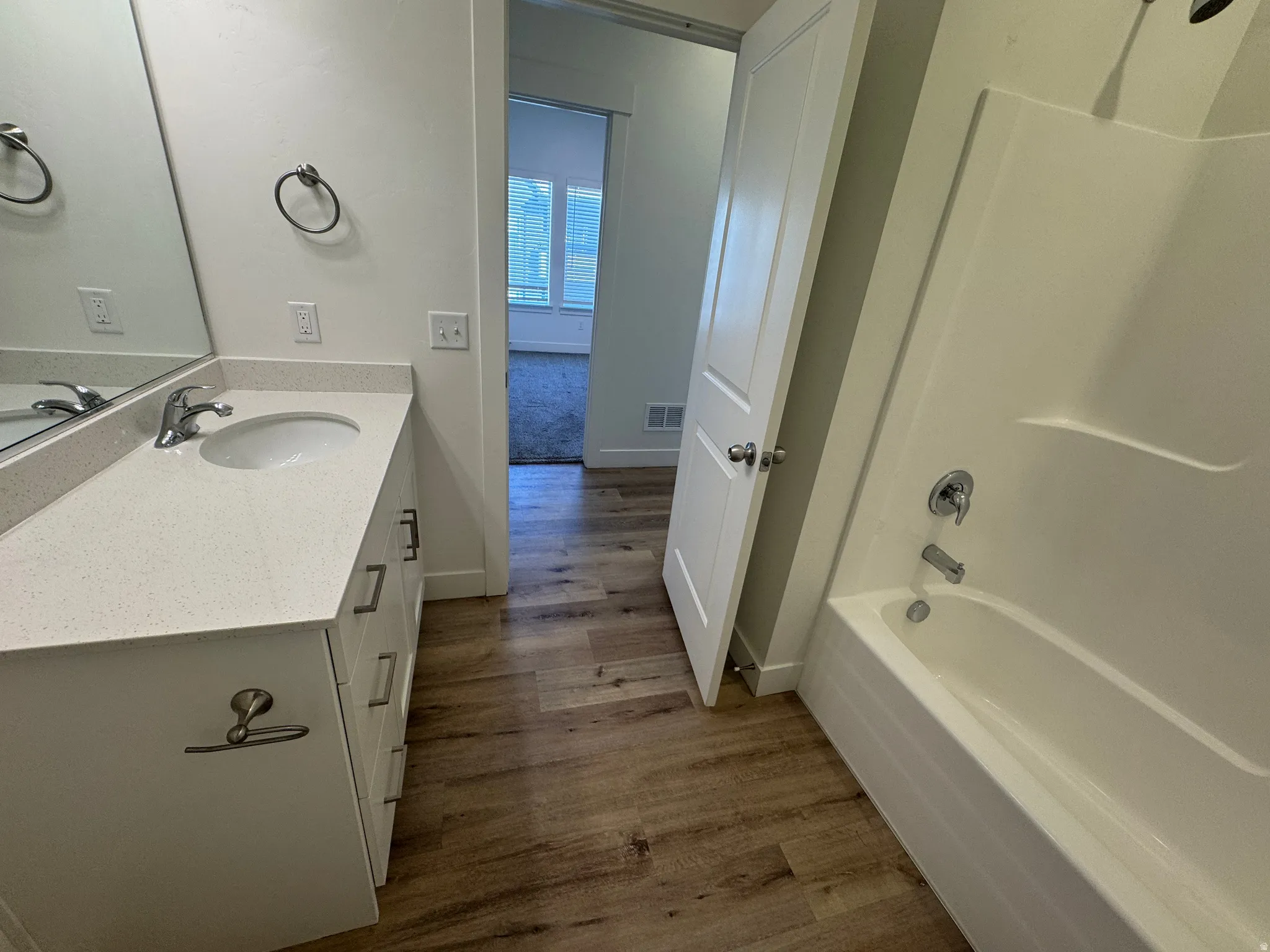Bathroom featuring a white vanity with an integrated sink, polished chrome faucet, and light-toned countertop