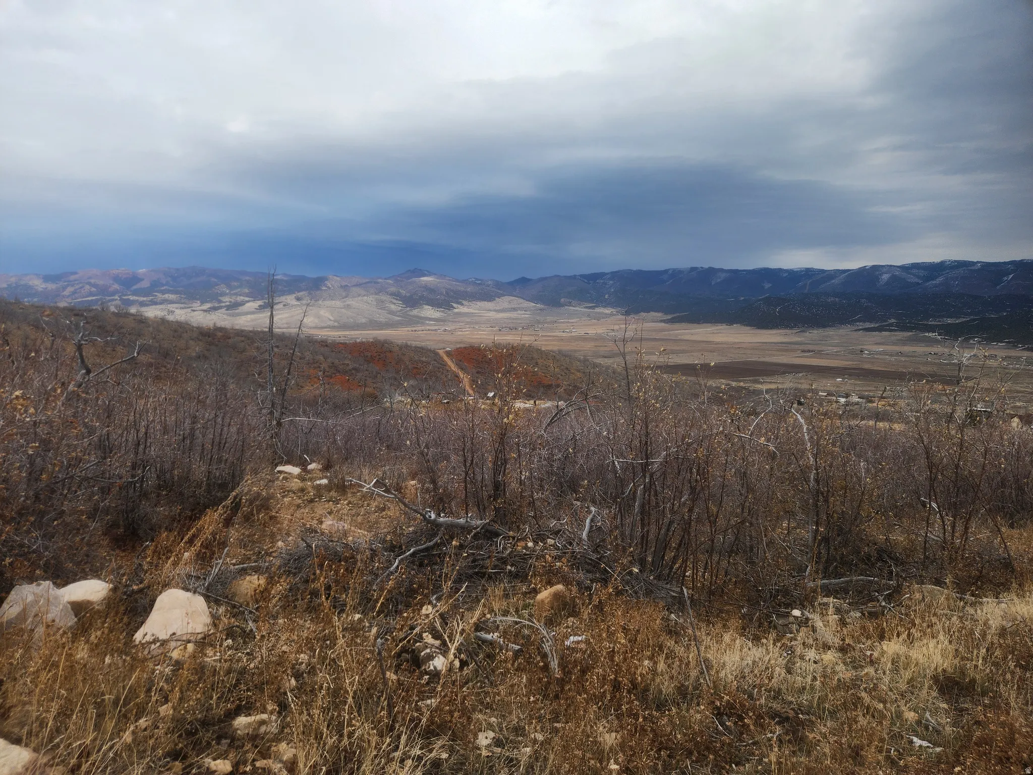 Expansive natural landscape with distant mountains, a wide valley, and varied terrain