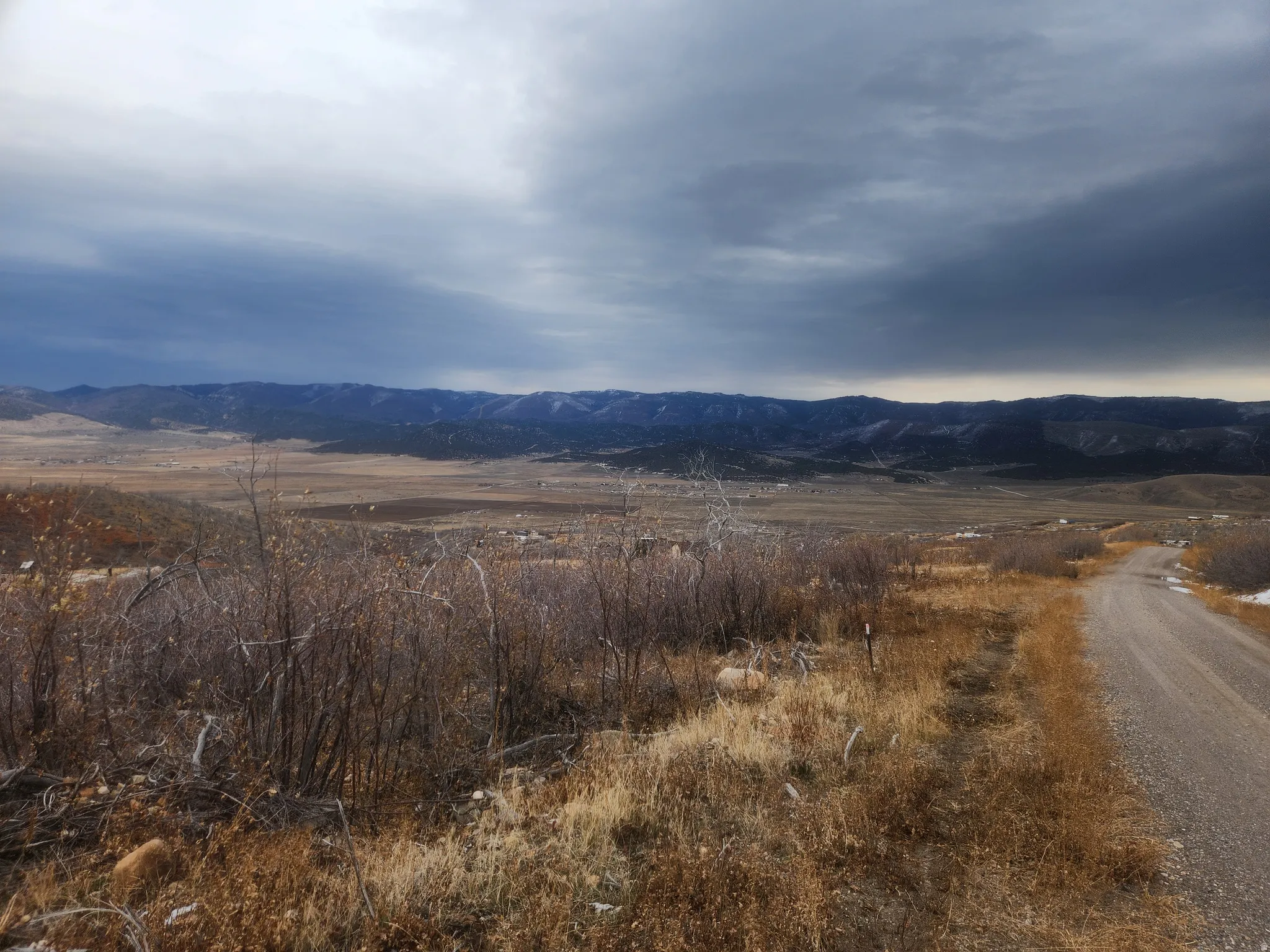 Expansive rural landscape featuring a gravel road, distant mountains, and open terrain