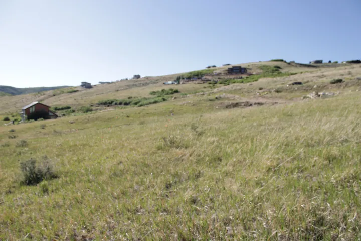Expansive hillside property featuring natural grass and distant structures