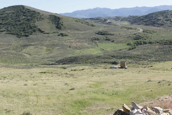 Expansive open terrain featuring natural vegetation, distant mountains, and a winding dirt road