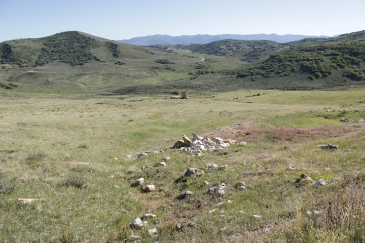 Expansive open land featuring natural grasses, scattered rock formations, and distant rolling hills