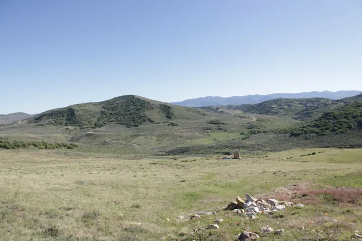 Expansive open land featuring rolling hills, distant mountains, and scattered natural vegetation