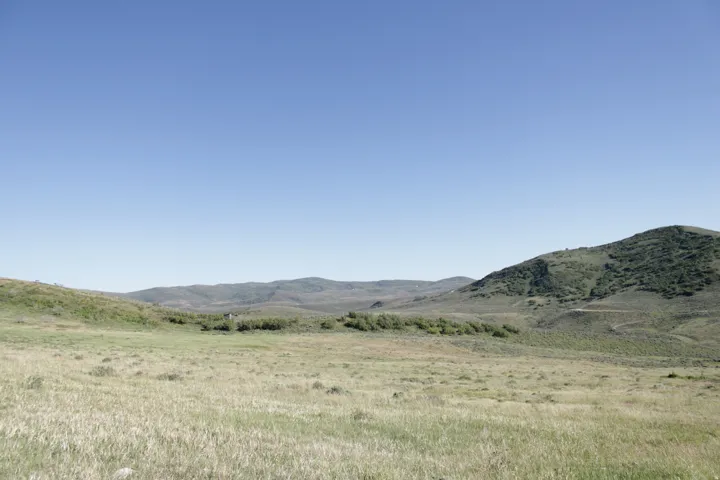 Expansive open land featuring rolling hills and distant mountains under a clear sky