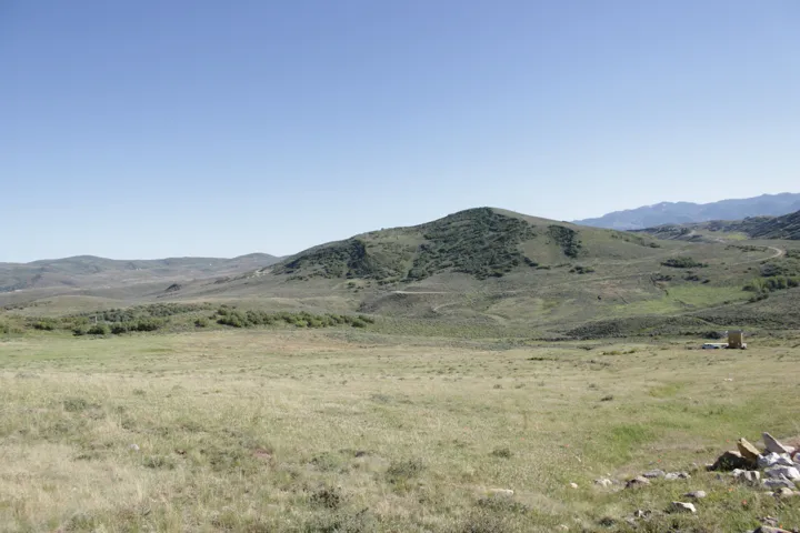 Expansive open pasture with rolling hills and distant mountainous terrain