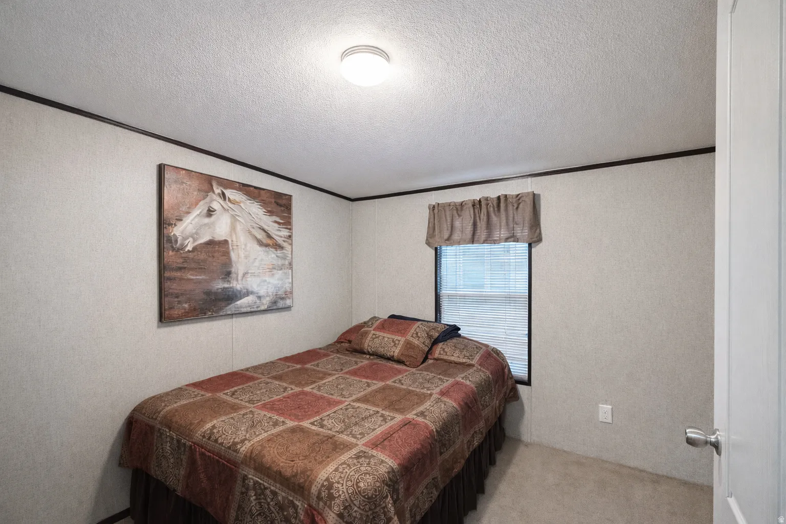 Comfortable bedroom featuring textured wall panels, contrasting dark trim, a window with blinds, and ceiling-mounted lighting