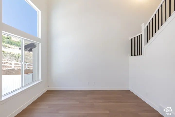 Expansive two-story windows, wood-finish flooring, white walls, and a staircase with black metal balusters