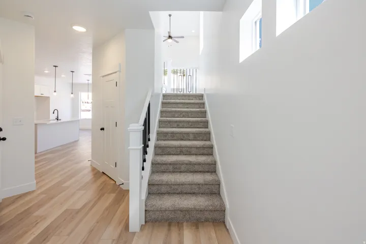 Carpeted staircase with black wrought iron railing and white newel post