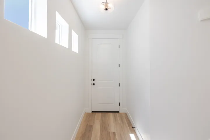 Recessed ceiling with an attached light fixture, wood-finish flooring, and multiple high-set windows