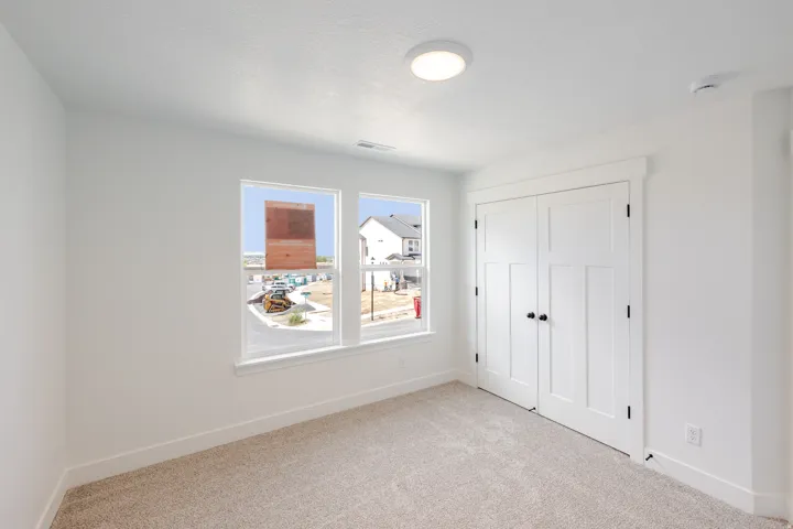 Neutral-toned carpeting, two panel-style windows with white trim, and a flush-mount ceiling light fixture