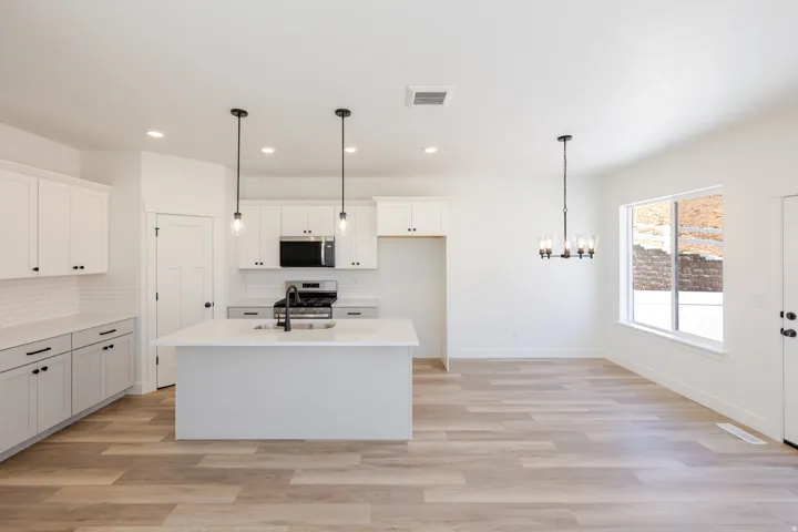 Kitchen featuring an island with a sink, white cabinetry with black hardware, stainless steel appliances, and wood-finish flooring