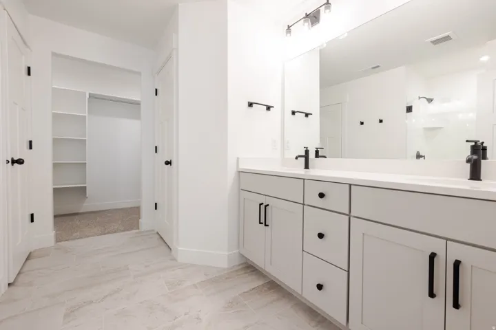 Dual vanity with matte black fixtures, light-toned countertops, and light gray cabinetry