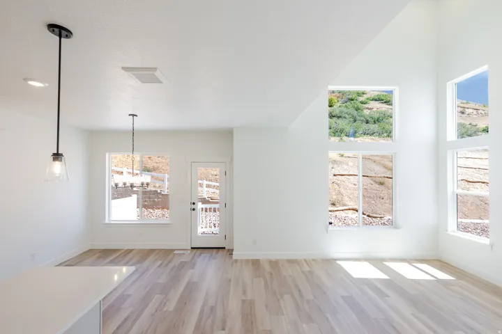Vaulted ceilings with abundant natural light, wood-finish flooring, recessed lighting, and a private patio with white railing