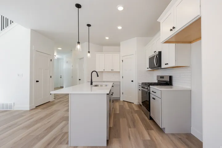 Kitchen featuring white cabinetry, subway tile backsplash, an island with countertop, and wood-finish flooring