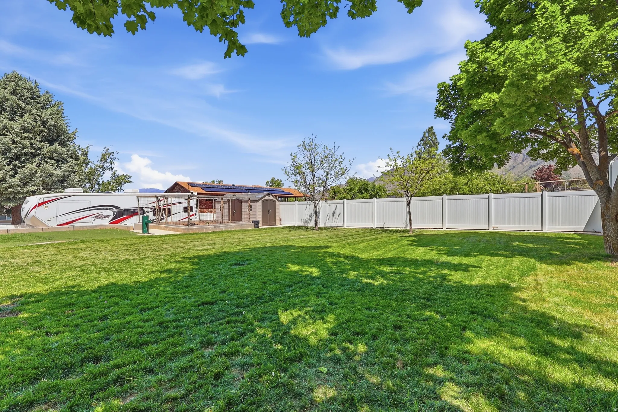Expansive green lawn with a white privacy fence