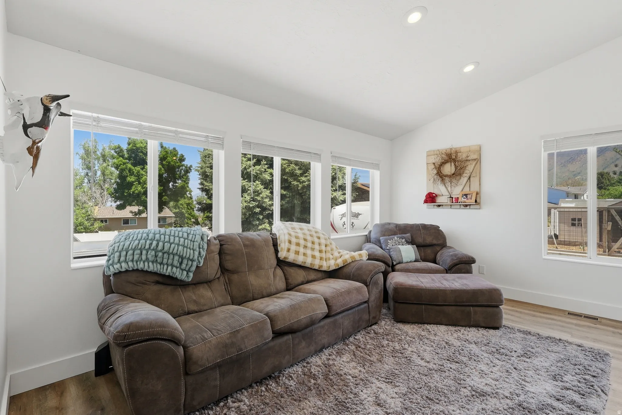 Bright interior space featuring multiple large windows, recessed ceiling lighting, and wood-finish flooring