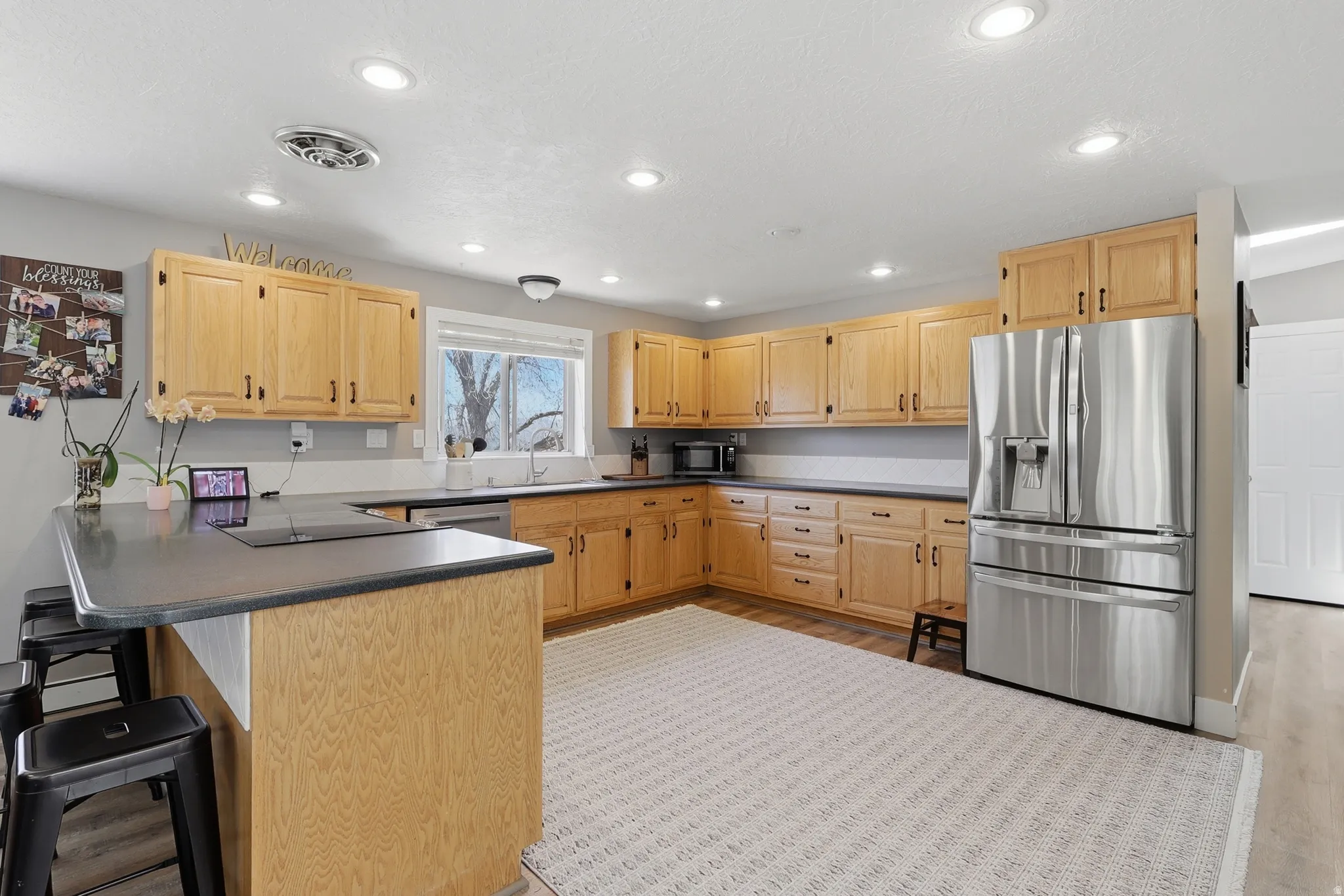 Kitchen featuring light wood cabinetry, dark countertops, and recessed lighting