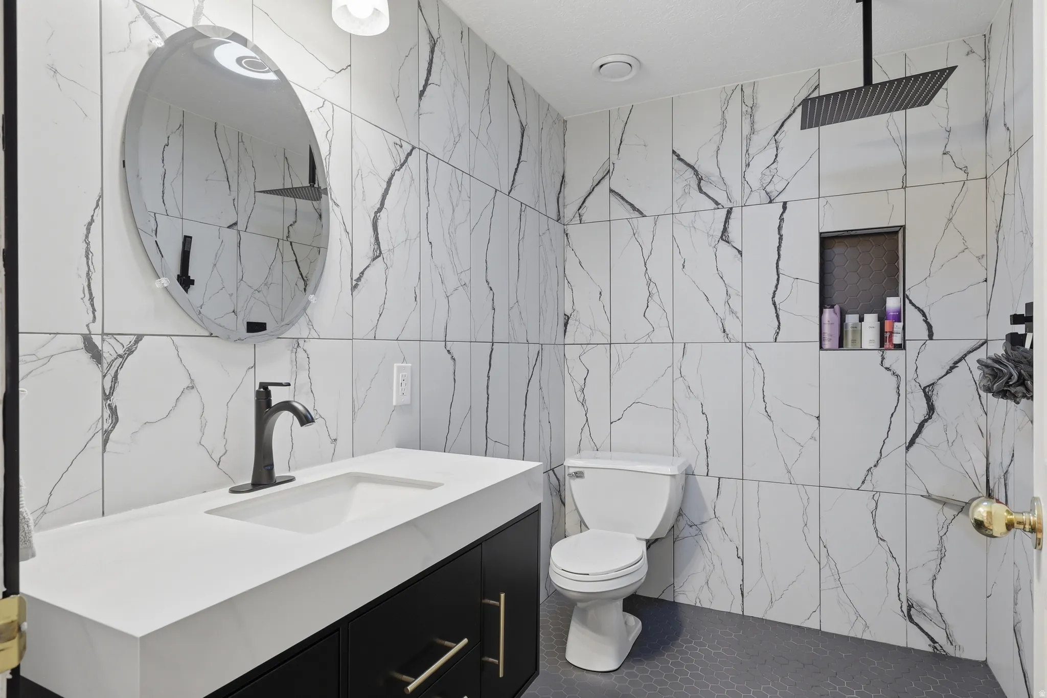 Contemporary bathroom featuring large format marble-look wall tiling, a rectangular vessel sink with a matte black faucet, and a wall-mounted matte black rainfall showerhead