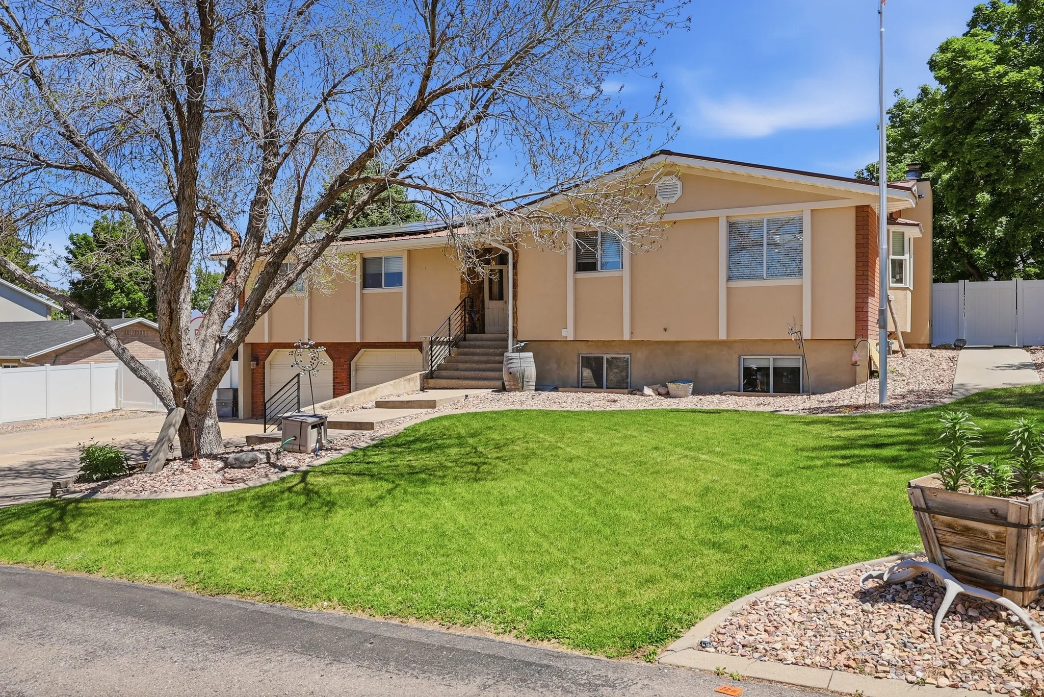 Split-level residence featuring a stucco exterior with brick accents and a prominent front lawn