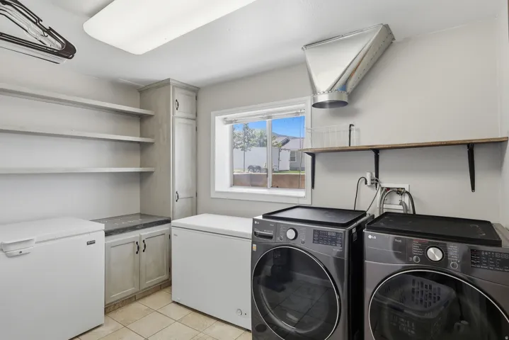Dedicated utility room with ample storage, featuring light-toned cabinetry, open shelving, and a built-in countertop