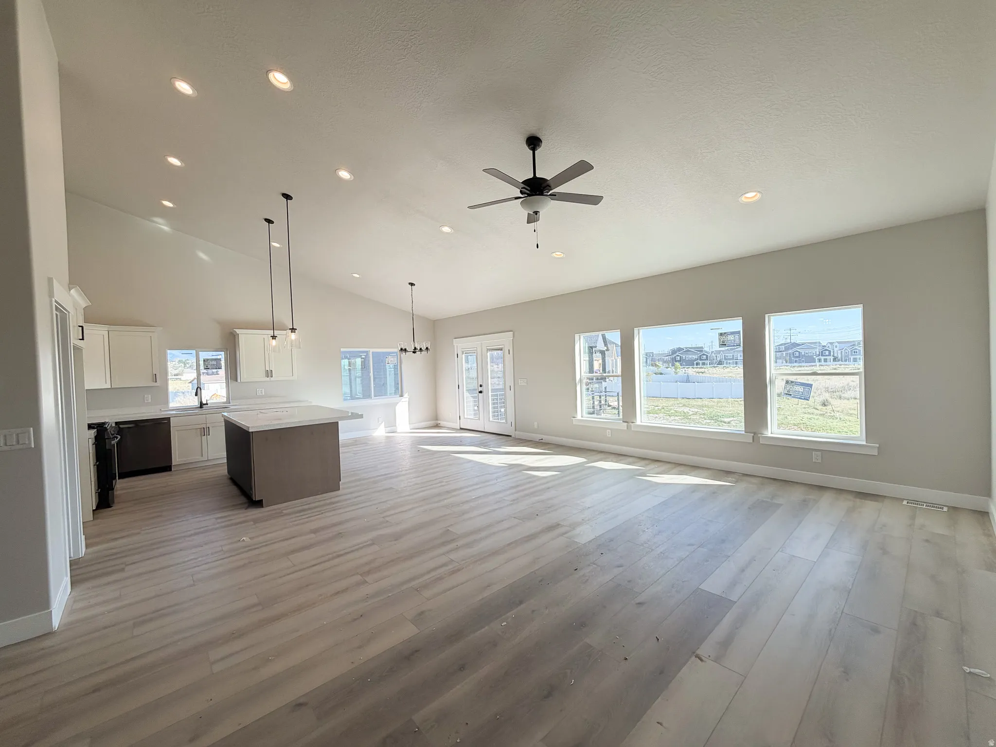 Open-concept living space featuring vaulted ceilings, recessed lighting, and wood-finish flooring