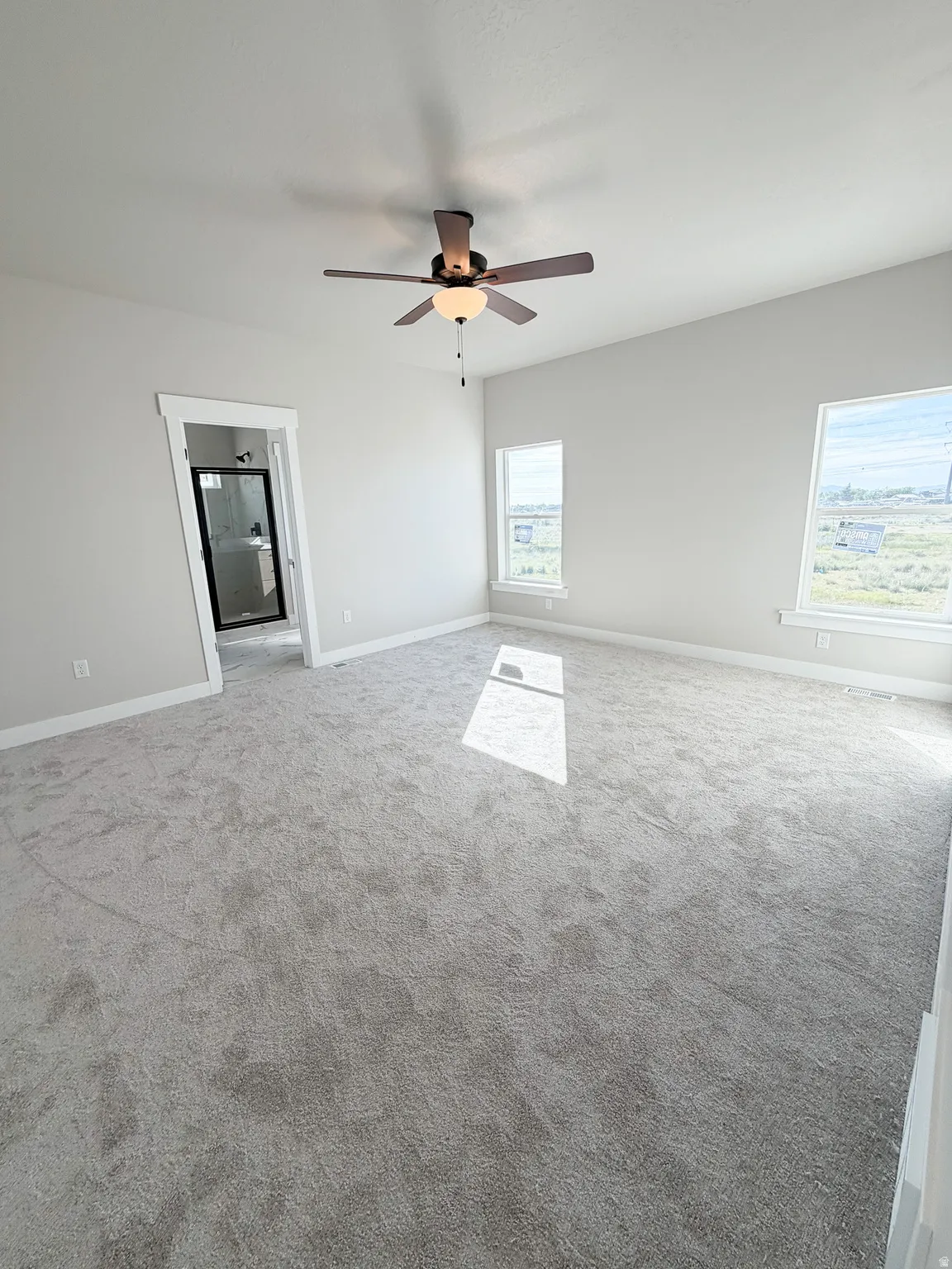 Spacious room featuring light gray carpeting and neutral wall tones