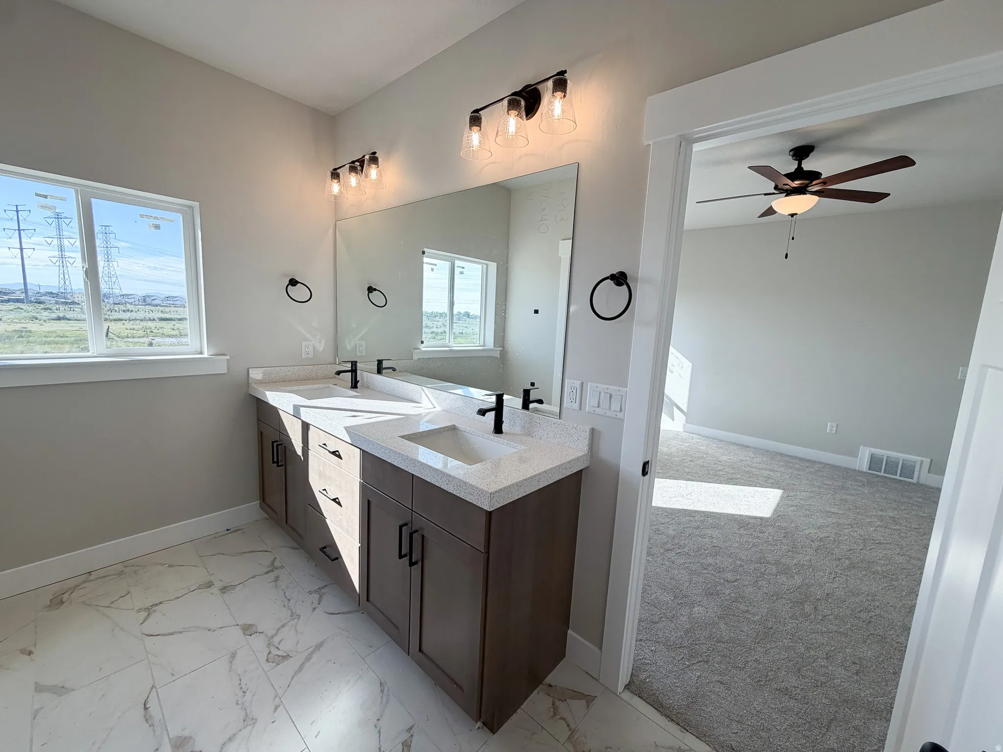 Bathroom featuring a dual vanity with quartz countertops, undermount sinks, and matte black fixtures