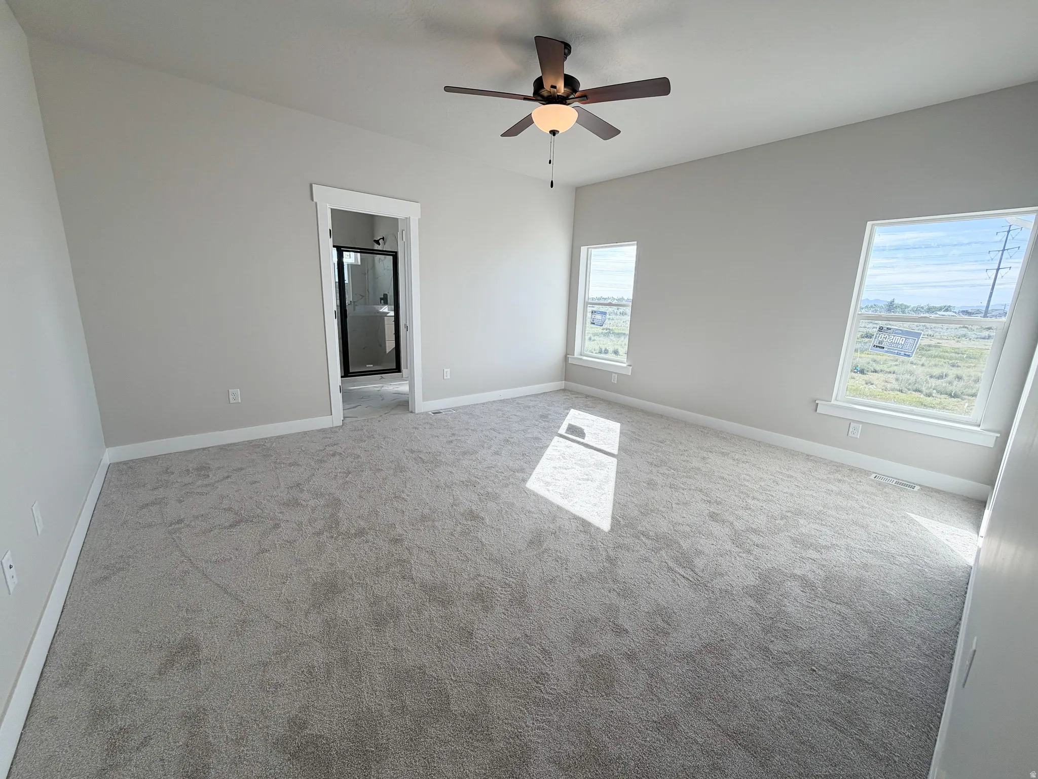 Carpeted room with a ceiling fan, light gray walls, and multiple windows