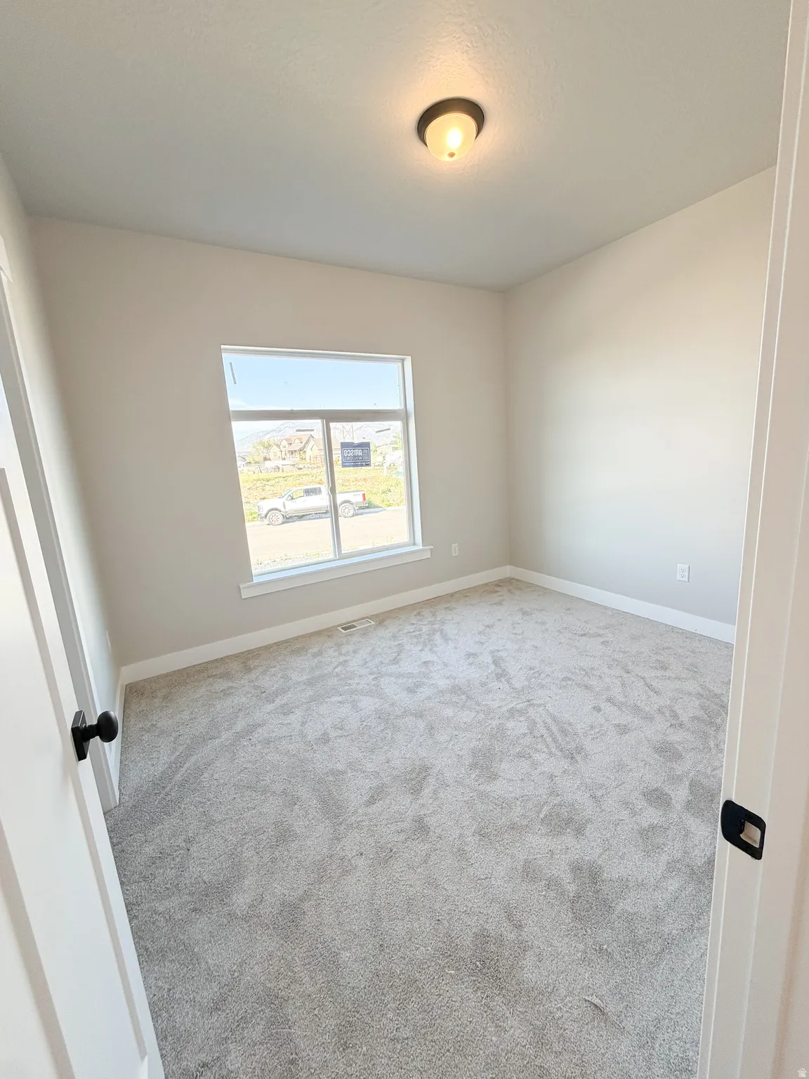 Neutral-toned room with light gray carpet, white baseboards, and a single window
