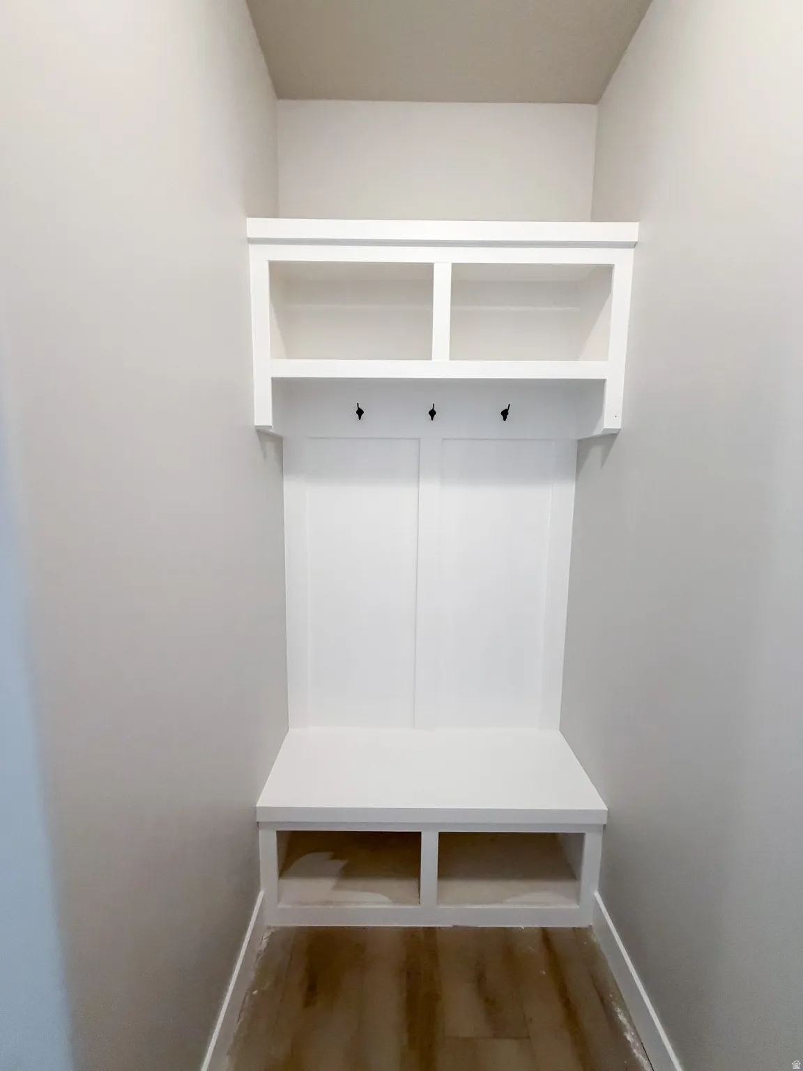 Built-in mudroom bench with white cabinetry, open shelving, and integrated coat hooks