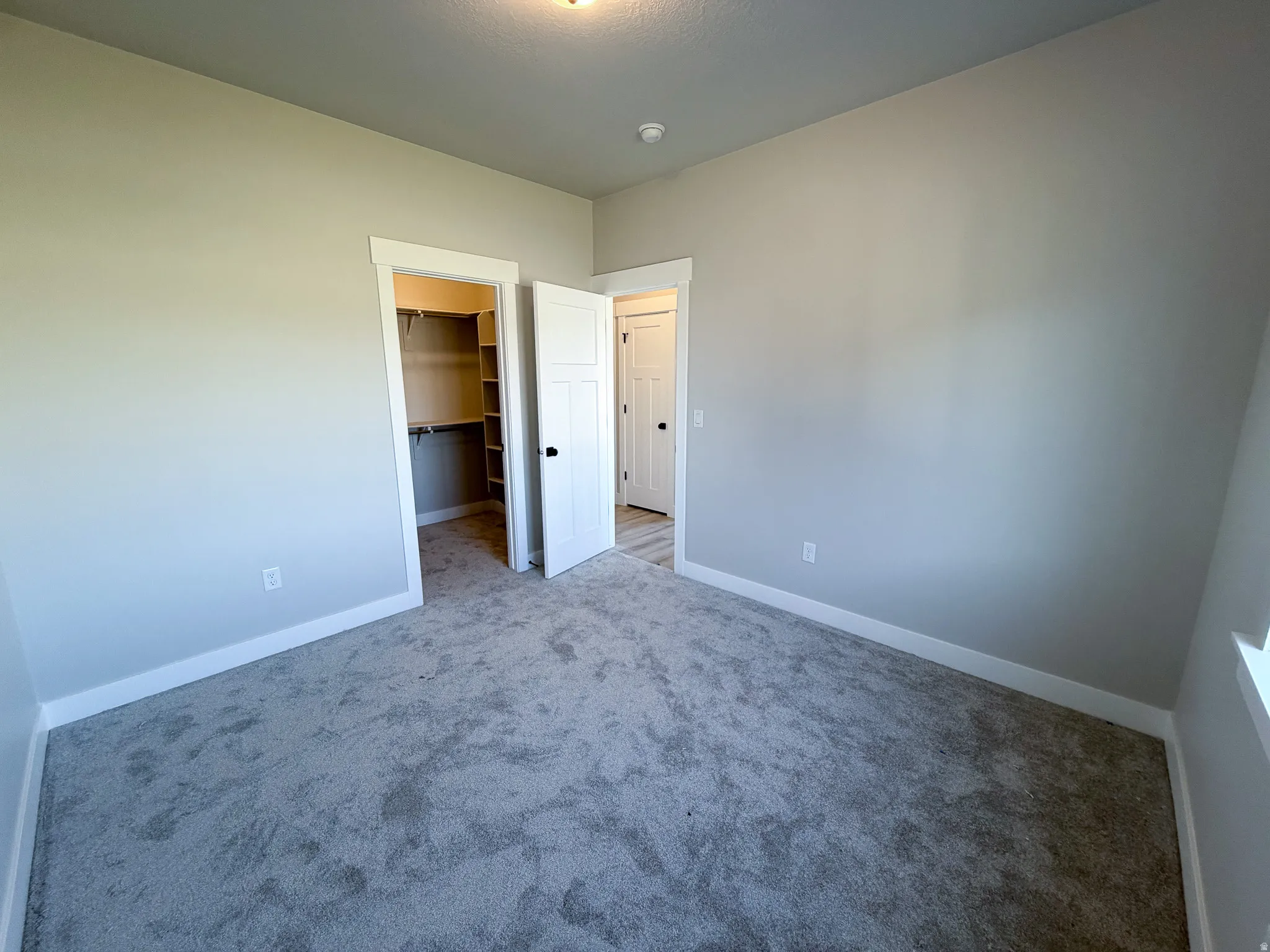 Neutral-toned room featuring plush grey carpeting and crisp white baseboards