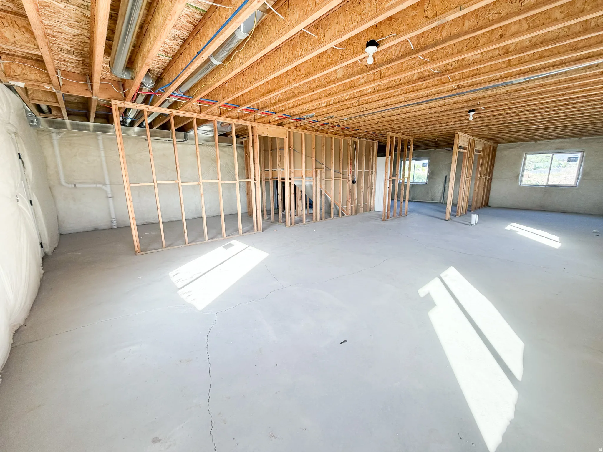 Unfinished basement featuring wood framing for future rooms, exposed ceiling joists, and concrete flooring
