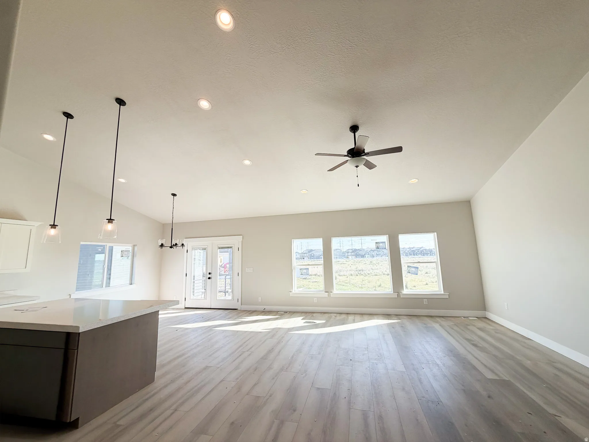 Open-concept living area featuring vaulted ceilings, recessed lighting, and wood-finish flooring